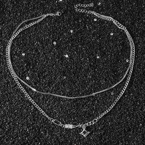 Collier double couche argenté avec cristaux noirs carrés et pendentif étoile sur sable