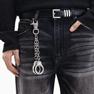 Détail d'une boucle tête de mort punk et pendentif menottes sur chaîne de pantalon