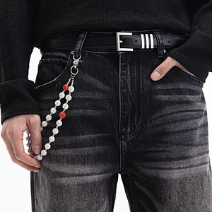 Détail de chaîne argentée avec perles Shamballa en cristal blanc et rouge sur jean