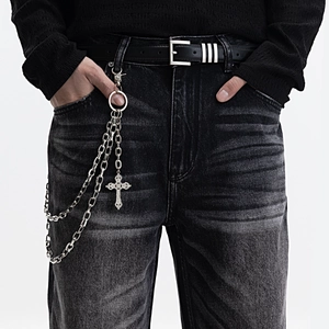 Detail of silver double-layered metal pants chain with a carved cross pendant on black denim