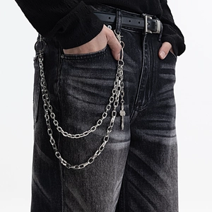 Three-layer silver metal pants chain with cross pendant on black washed denim jeans