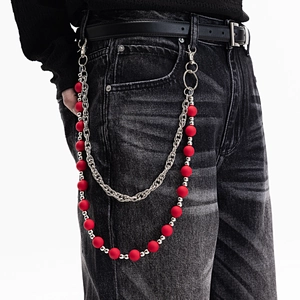 Détail d'une chaîne de pantalon à perles colorées sur un jean noir pour un look tendance