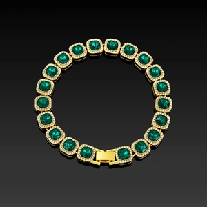 Macro detail of a gold-plated tennis bracelet featuring square emerald-cut green stones