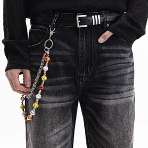 Détail d'une chaîne de pantalon sport avec perles basketball et baseball sur un jean noir