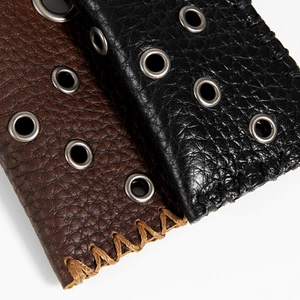 Detailed macro view of retro leather lighter case with cross-stitching and silver eyelets