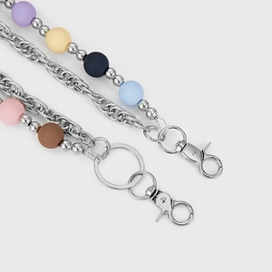 Détail macro de perles colorées mates et chaîne en métal argenté avec fermoir mousqueton