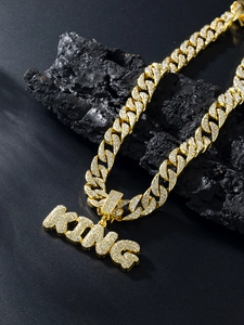 Macro detail of gold Cuban chain and KING pendant encrusted with sparkling rhinestones