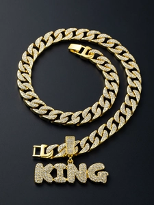 Macro shot of gold-plated iced out Cuban link chain and KING letter pendant with zircons