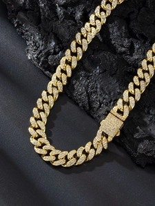 Dettaglio catena cubana da 13 mm in oro con cristalli bianchi su sfondo di roccia nera