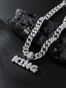 Macro shot of iced out silver Cuban chain with diamond encrusted KING letter pendant