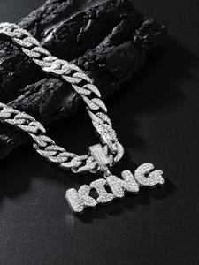Macro shot of silver hip-hop Cuban link chain with iced out KING letter pendant