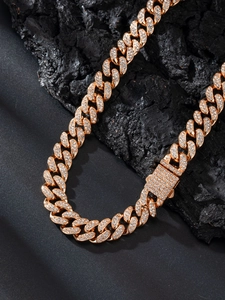 Dettaglio catena cubana dorata 13mm con pietre scintillanti su roccia nera