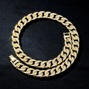 Détail macro d'une chaîne cubaine 14mm dorée sertie de strass sur satin noir