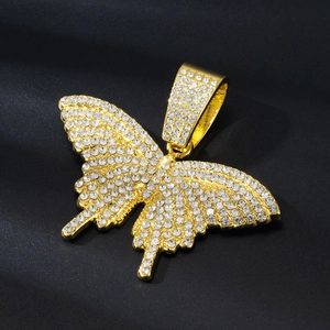 Close-up of gold plated butterfly pendant with sparkling white crystals on black background