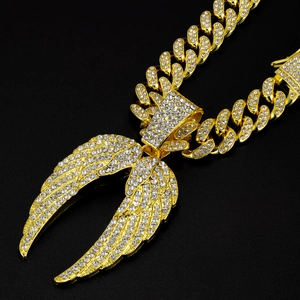 Détail du pendentif ailes d'ange serti de cristaux avec chaîne cubaine dorée