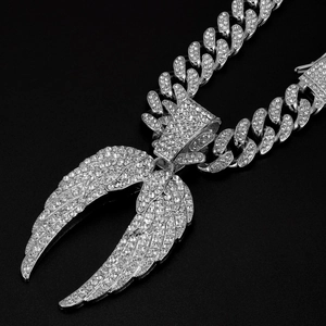 Détail du pendentif ailes serti de cristaux sur une chaîne à gros maillons