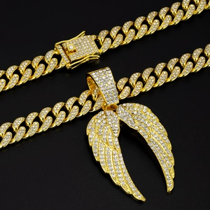 Gros plan sur une chaîne cubaine dorée hip-hop avec un pendentif ailes d'ange luxueux