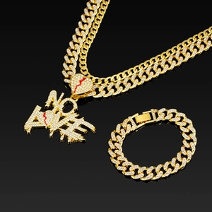 Close-up of iced out gold cuban chain and NO LOVE pendant with broken heart detail