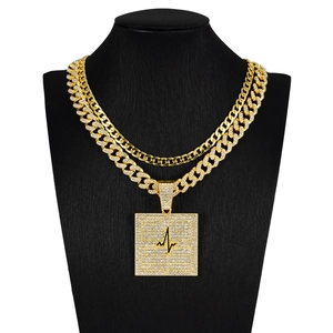 Détail du pendentif carré doré avec motif ECG et strass sur une chaîne à mailles cubaines