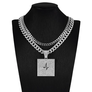 Détail de la double chaîne cubaine avec pendentif carré incrusté de diamants et électrocardiogramme