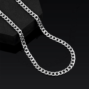 Macro shot of 7mm polished silver curb chain with high metallic luster on gray blocks