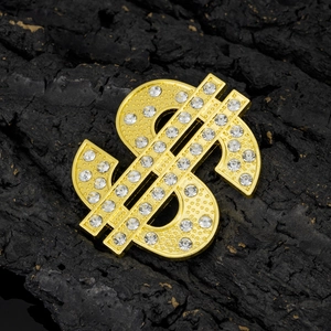Golden dollar sign pendant with white rhinestones and textured metal on dark wood background