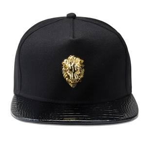 Detail of golden lion head emblem on black twill hip hop cap with crocodile skin brim