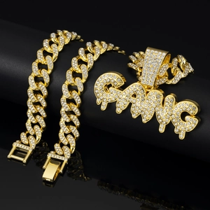 Close-up of iced out GANG pendant and gold Cuban chain necklace with sparkling crystals