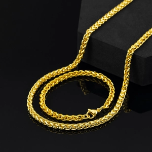 Détail macro d'un collier chaîne épi dorée de 5mm avec fermoir mousqueton sur fond noir