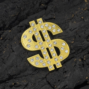 Detail of gold-plated dollar sign charm with white rhinestones on textured black stone