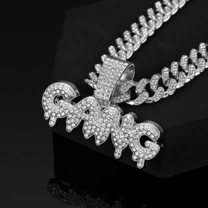 Macro shot of silver Cuban link chain and diamond encrusted GANG letter pendant