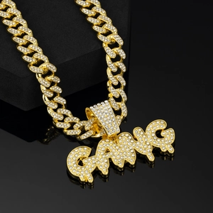 Close-up of golden GANG letter pendant with iced-out white rhinestones on Cuban link chain