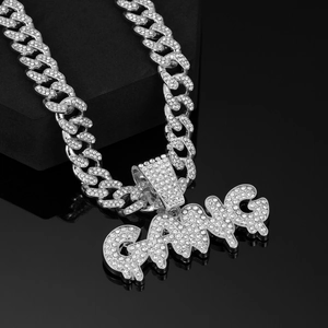 Close-up of iced-out GANG pendant on a chunky silver Cuban link chain with white crystals