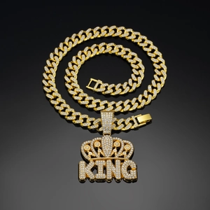 Close-up of golden Cuban link necklace with iced-out KING crown pendant on black background