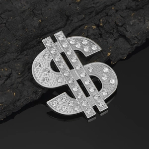 Macro view of silver plated metal dollar sign accessory with white rhinestones on black background