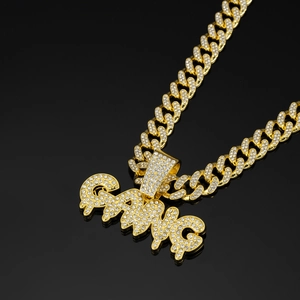 Macro shot of gold Cuban link chain and GANG pendant iced out with sparkling crystals