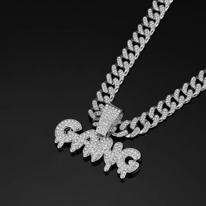 Macro shot of silver hip-hop Cuban link chain with iced-out GANG letter pendant