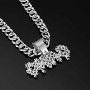 Macro close-up of silver GANG letter pendant with diamond-like texture on Cuban link chain