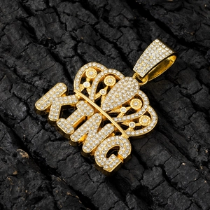 Macro shot of iced-out gold KING crown pendant with sparkling crystals on charcoal background