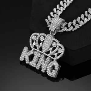 Macro shot of silver hip-hop KING crown pendant with iced-out crystals on a Cuban chain