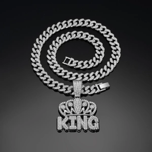 Macro shot of silver Cuban link chain with iced out KING crown pendant on black reflective base