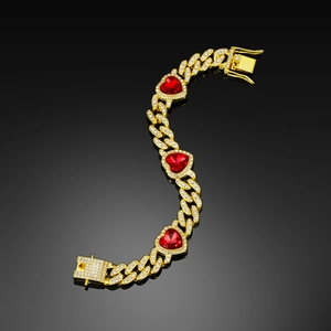Detail of gold Cuban chain with red heart zircons and pavé diamonds on black mirror