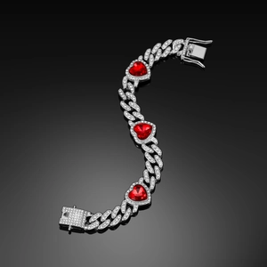 Macro shot of silver Cuban link necklace featuring three red heart-shaped crystals