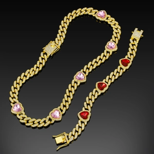 Close-up of golden Cuban link necklace and bracelet with pink heart-shaped gems