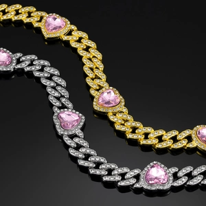 Detailed macro view of gold and silver Cuban link necklaces with pink heart crystals