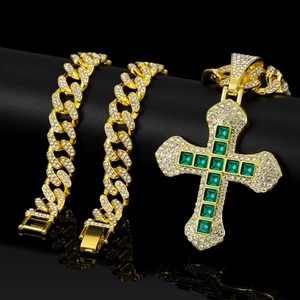 Macro shot of hip-hop cuban chain with green square gems set in a gold cross pendant