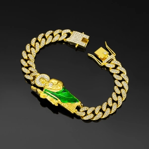 Macro shot of gold Cuban link bracelet with St. Jude pendant in green enamel and diamonds