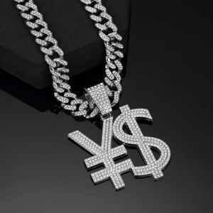 Macro shot of silver Cuban chain with diamond-encrusted dollar and yen symbol pendants