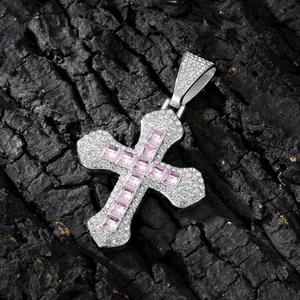 Detailed view of silver cross pendant with pink square stones on black textured background