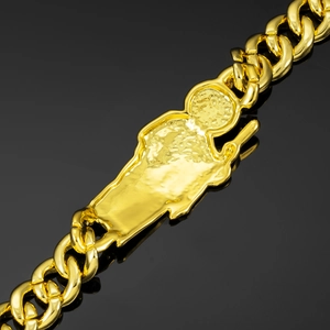 Macro detail of gold-toned Cuban link bracelet with St. Jude religious embossed plate